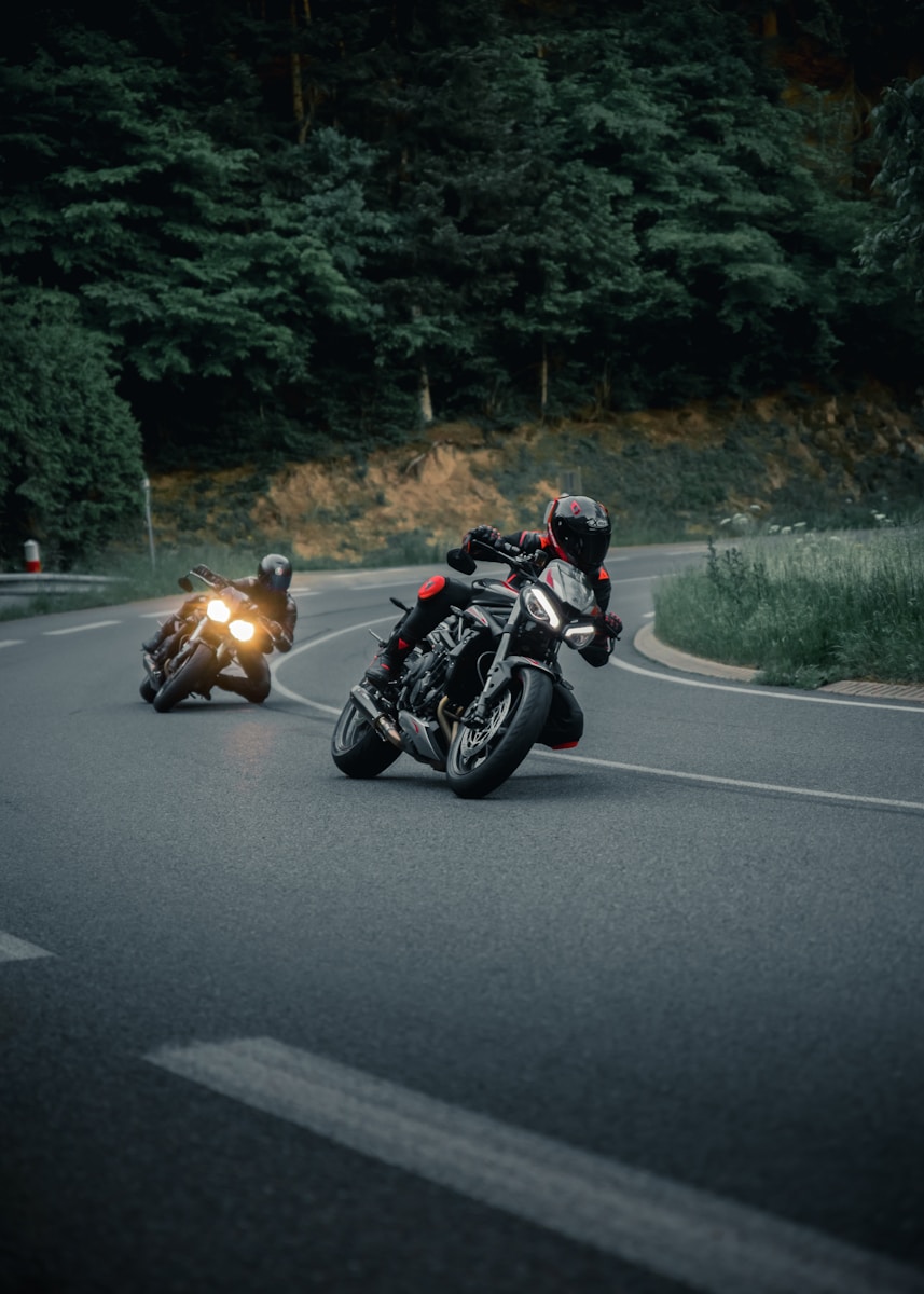 a couple of people riding motorcycles down a curvy road with motorcycle safety in mind