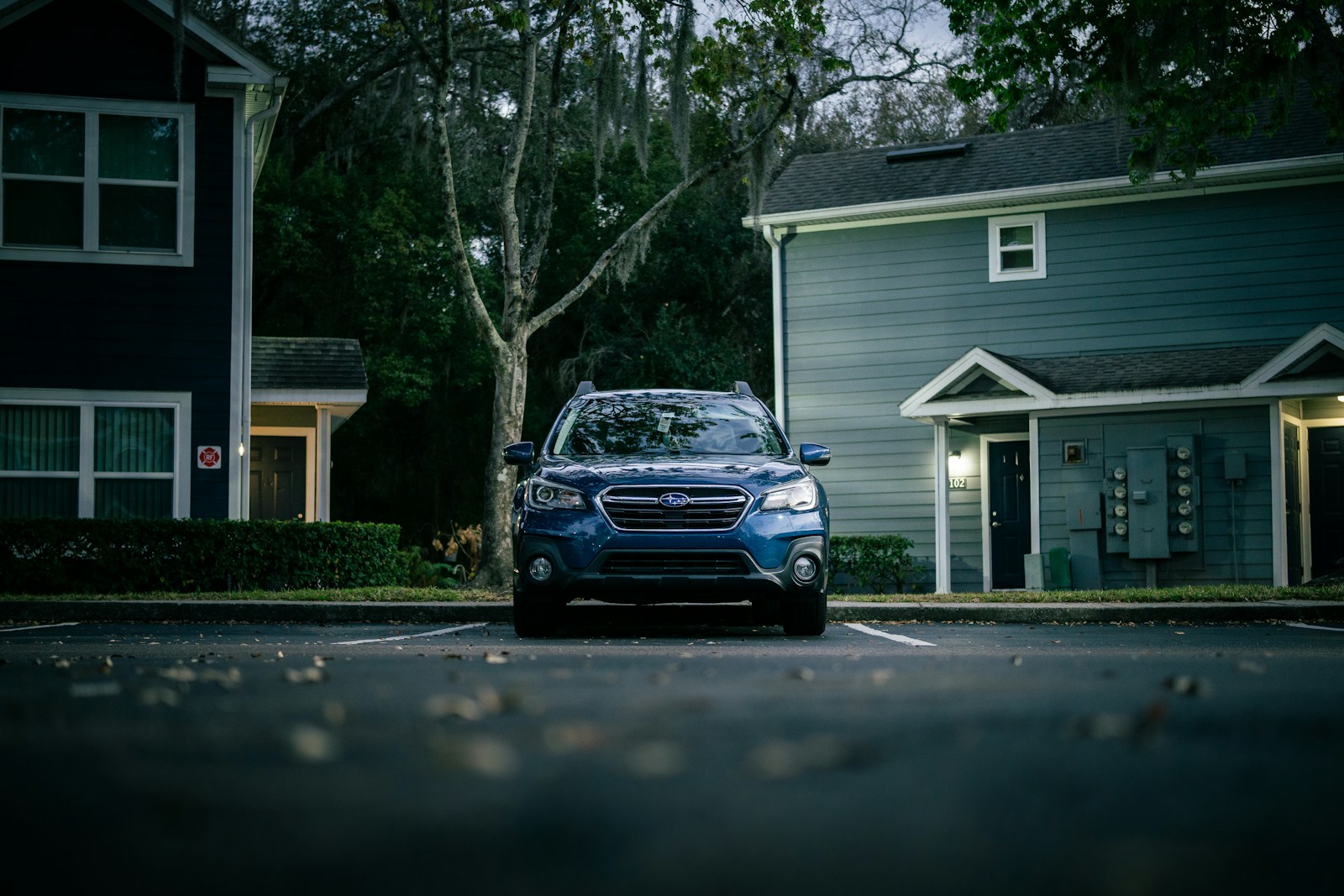 Blue suv parked in front of apartment buildings.